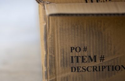 An open cardboard shipping carton printed with the headings PO number, item number and description.